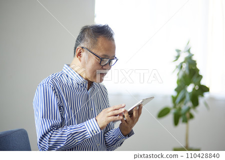 日本老年男子在客廳使用平板電腦 日本老年男子在客廳使用平板電腦 110428840