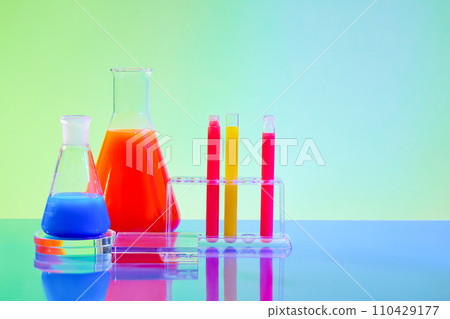 Colorful liquids in test tubes and glass lab flasks against a blue-green gradient backdrop. Abstract laboratory concept in a front-view composition. Colorful liquids in test tubes and glass lab flasks against a blue-green gradient backdrop. Abstract laboratory concept in a front-view composition. 110429177