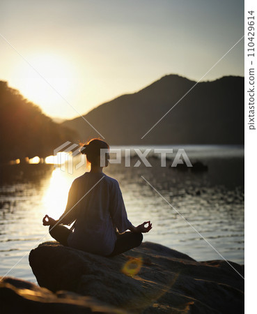A woman meditating in a yoga pose at dawn AI image AI generated image 110429614