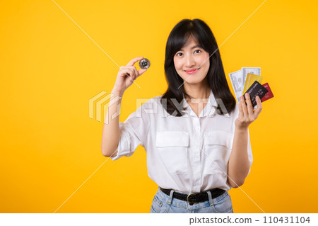 Capture the essence of digital currency with stunning portrait of young Asian woman confidently holds digital currency, cash, credit card, and smartphone. The digital currency concept. 110431104