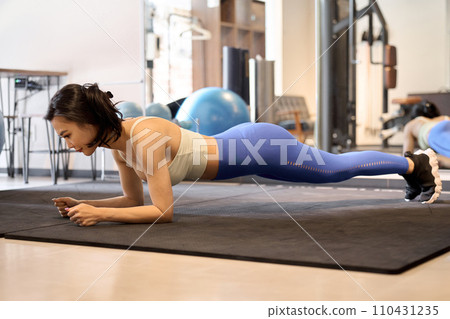 Woman training her core with forearm plank 110431235