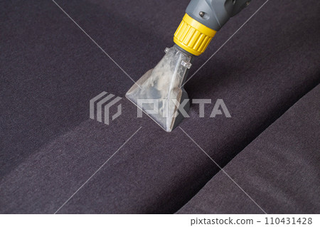 Cleaning the sofa with a special washing vacuum cleaner from dirt. Dry cleaning of sofas and upholstered furniture, close-up. Copy space for text Cleaning the sofa with a special washing vacuum cleaner from dirt. Dry cleaning of sofas and upholstered furniture, close-up. Copy space for text 110431428
