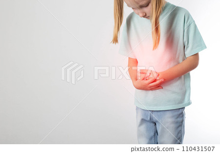 A little blonde girl of seven years old stands and holds her lower abdomen on a white background. Concept of diseases of the urinary system in children. Inflammation of the bladder, cystitis and A little blonde girl of seven years old stands and holds her lower abdomen on a white background. Concept of diseases of the urinary system in children. Inflammation of the bladder, cystitis and 110431507