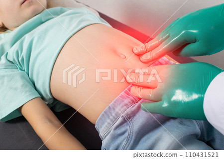 A doctor palpates the abdomen of a seven-year-old little girl who has pain and colic in her abdomen. Concept of intestinal diseases in children, spasms and diarrhea, close-up 110431521
