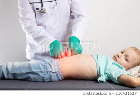 A doctor in green medical gloves is palpating the abdomen of a little seven-year-old girl. Stomach disease, gastritis and peptic ulcer in children, indigestion. Copy space for text 110431527
