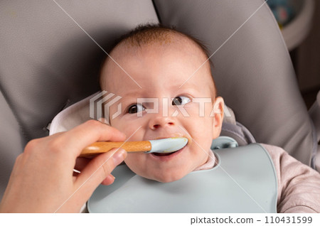 A little boy caucasian has been trying porridge and fruit puree for 6 months. Weight gain in infants, caloric content of food, close-up A little boy caucasian has been trying porridge and fruit puree for 6 months. Weight gain in infants, caloric content of food, close-up 110431599