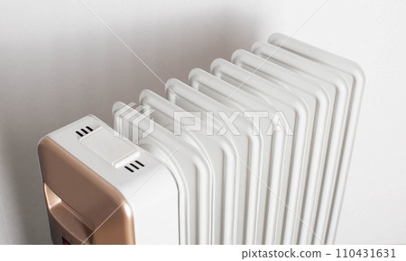 Modern electric oil heater on a white background. Heating the room. Heating season in apartments, close-up 110431631