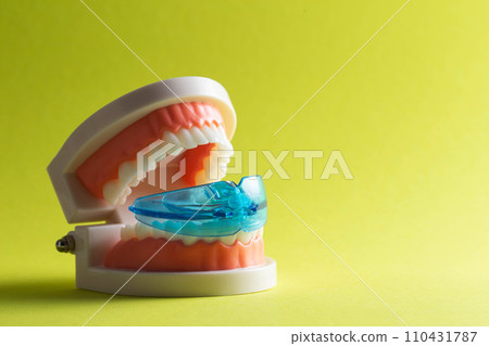 Dental mouth guard for bruxism with a mock-up of a dental jaw on a yellow background. Concept for treatment and protection of teeth from grinding during sleep in children. Copy space for text 110431787