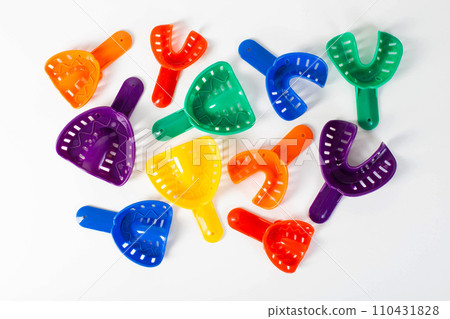 Multi-colored dental spoons for taking an impression of the dental jaw on a white background. Orthodontics in dentistry. 110431828