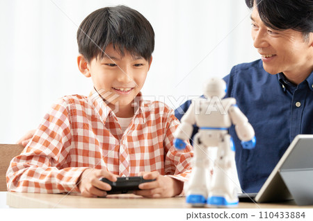一個男孩操作機器人，他的父親在旁邊看著 110433884