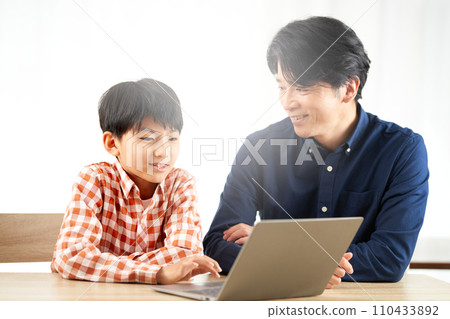 Elementary school boy and adult man staring at laptop screen 110433892