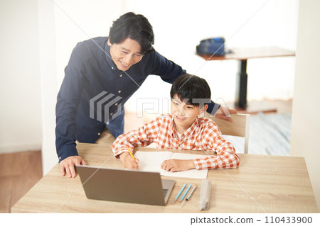 Elementary school boy studying while looking at a PC and his father watching with a smile 110433900