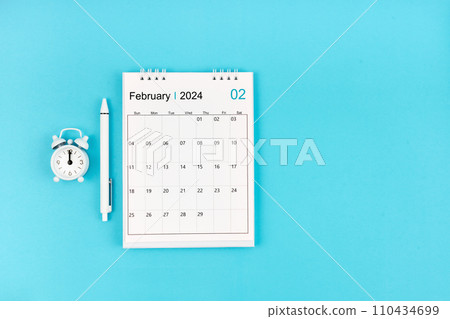 February 2024, Monthly desk calendar for 2024 year and pen with alarm clock on blue. February 2024, Monthly desk calendar for 2024 year and pen with alarm clock on blue. 110434699
