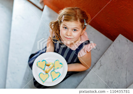 Happy little preschool girl celebrating birthday. Closeup of child with homemade biscuite cake, indoor. Happy healthy kid indoors 110435781
