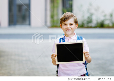 Happy little kid boy with backpack or satchel. Schoolkid on the way to school. Healthy adorable child outdoors With chalk desk for copyspace. Back to school or school's out. Happy little kid boy with backpack or satchel. Schoolkid on the way to school. Healthy adorable child outdoors With chalk desk for copyspace. Back to school or school's out. 110435963