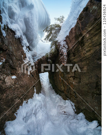 Narrow path through snow drifts between rocks, a stone vault, a cave. Narrow path through snow drifts between rocks, a stone vault, a cave. 110436924