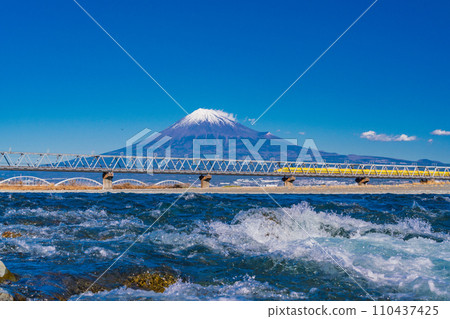 (Shizuoka Prefecture) Shinkansen Doctor Yellow crosses the rapid-flowing Fuji River iron bridge with Mt. Fuji in the background 110437425