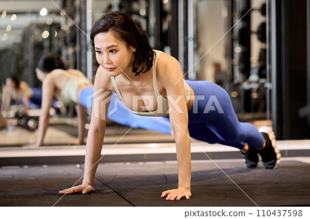 A woman training her upper body with push-ups 110437598
