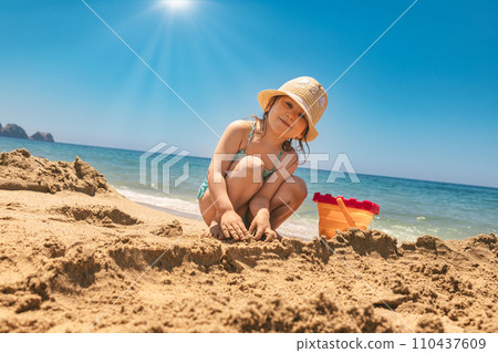 Child wearing protective sunhat playing on a beach Child wearing protective sunhat playing on a beach 110437609