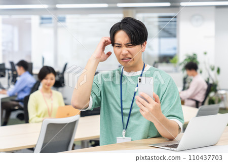 一位年輕的工程師在辦公室看智能手機 110437703