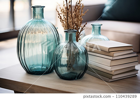AI-generated content. Home decor in marine style, glass blue vases with dry branches and books on table. Interior details of living room of country cottage at summer resort. 110439289