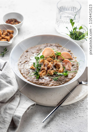 Thick lentil soup with croutons and meat chips served for dinner on white background Thick lentil soup with croutons and meat chips served for dinner on white background 110441023