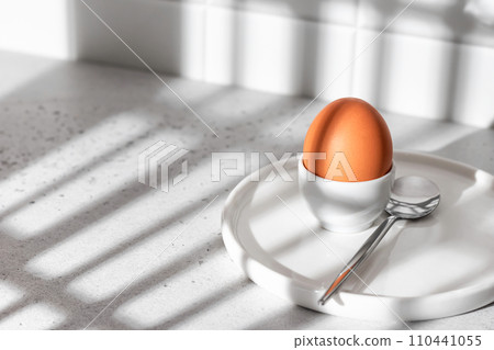 Boiled egg in hard light with window shadows on white kitchen background. Light protein breakfast concept, minimalism, high key 110441055