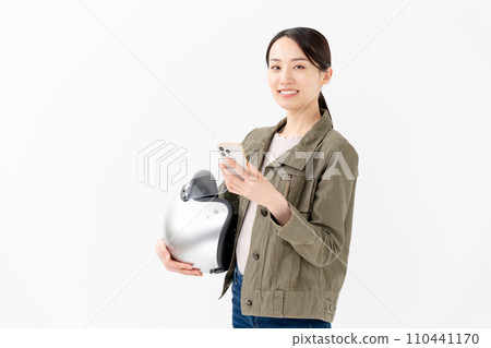 A woman holding a helmet and looking at a smartphone A woman holding a helmet and looking at a smartphone 110441170