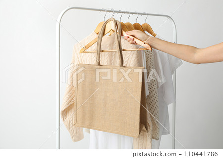 A bag hangs on a hanger with clothes 110441786