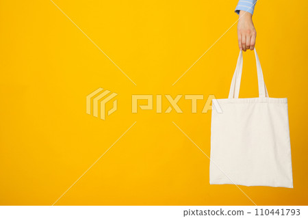 White bag in hand on yellow background 110441793