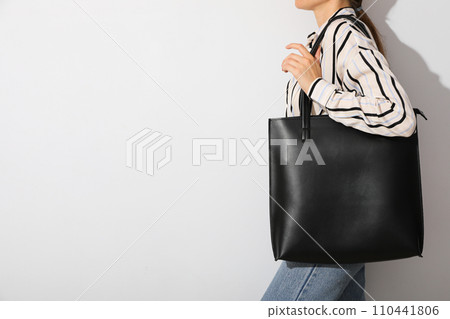 The woman has a black bag on her shoulder 110441806