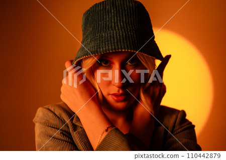 Fashionable model wearing trendy sunglasses and stylish hat against orange background in studio Fashionable model wearing trendy sunglasses and stylish hat against orange background in studio 110442879