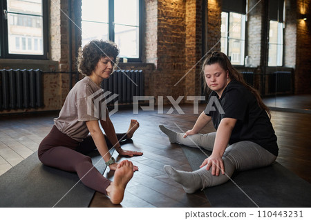 Trainer and active woman sitting on mats Trainer and active woman sitting on mats 110443231