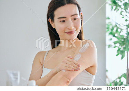 30多歲的女性在上臂塗霜保養身體 30多歲的女性在上臂塗霜保養身體 110443371
