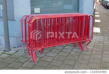 Metal red painted fences on a street corner 110443494