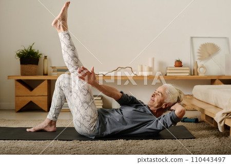 Woman stretching arm towards raised leg Woman stretching arm towards raised leg 110443497