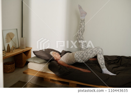 Fit woman keeping stretched leg raised 110443635