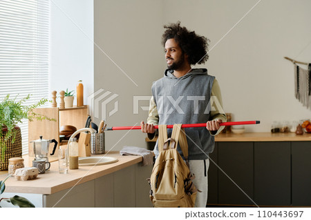 Happy guy lifting backpack on stick 110443697