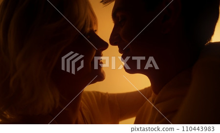 Young couple kissing each other during romantic date under vibrant orange neon illumination 110443983