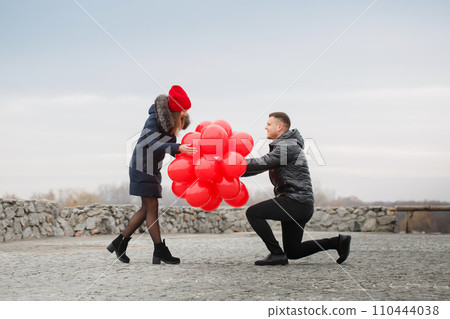 Young couple with red balloons, outdoors 110444038