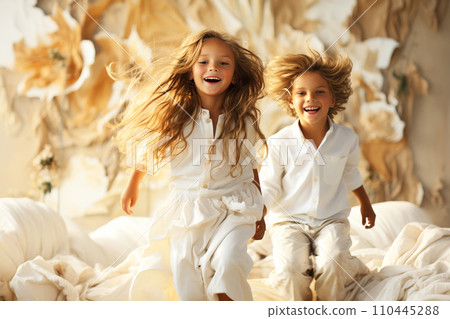 Cheerful children, sisters, brothers play and jump on the bed in the bedroom. 110445288