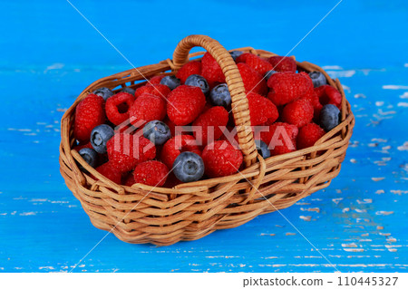 Basket with berries on old boards 110445327