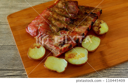 Baked pork ribs with potatoes on a wooden tray Baked pork ribs with potatoes on a wooden tray 110445409