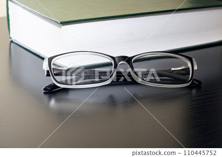 Black glasses and a book on a wooden table Black glasses and a book on a wooden table 110445752