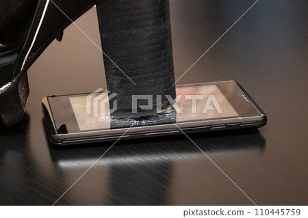 Broken screen telephone with heel shoes closeup Broken screen telephone with heel shoes closeup 110445759