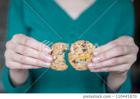 Hand holding cookies close-up. The process of eating cookies. A quick and sweet snack in the form of cookies. 110445870