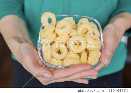 Hand holding corn rings close-up. Round yellow chips are a quick snack for kids. Hand holding corn rings close-up. Round yellow chips are a quick snack for kids. 110445874