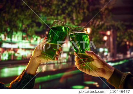 Two people sitting in pub at bar counter and drinking green traditional beer. Selective focus. Blurred. 110446477