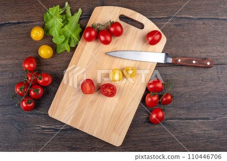 Top view of a cutting board with a kitchen knife and tomatoes. Top view of a cutting board with a kitchen knife and tomatoes. 110446706