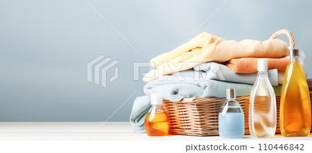 AI-generated content. Colorful clothes and towels in a wicker basket, various detergents for washing on a bright blue background AI-generated content. Colorful clothes and towels in a wicker basket, various detergents for washing on a bright blue background 110446842